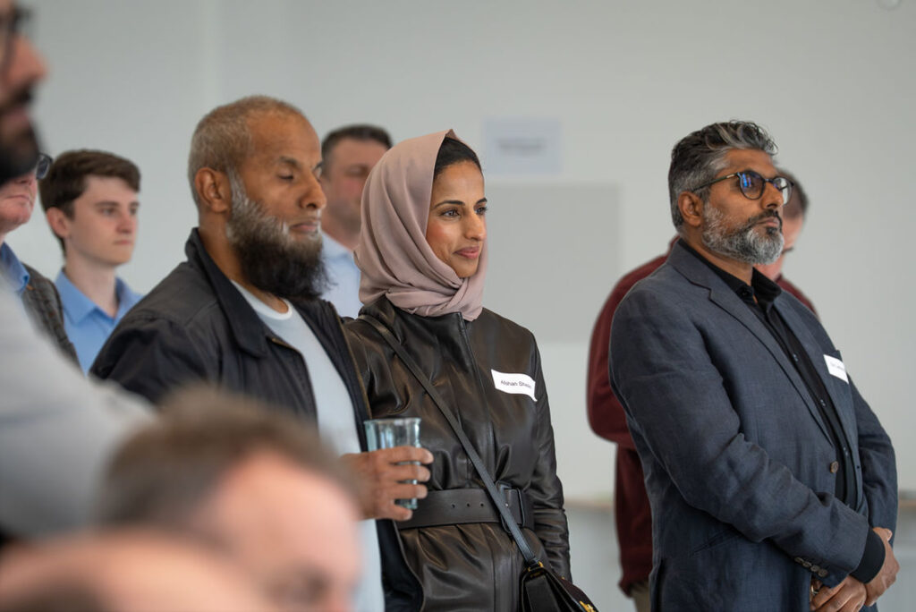 Three attendees talking during a networking break at the Hub