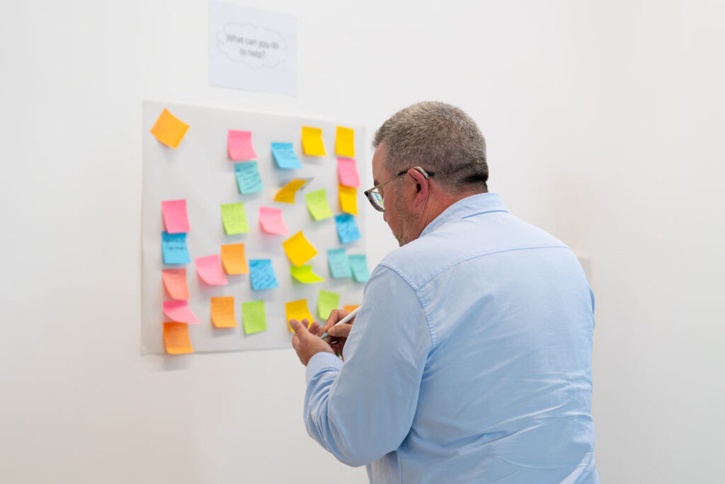 A participant adding sticky notes to a workshop board