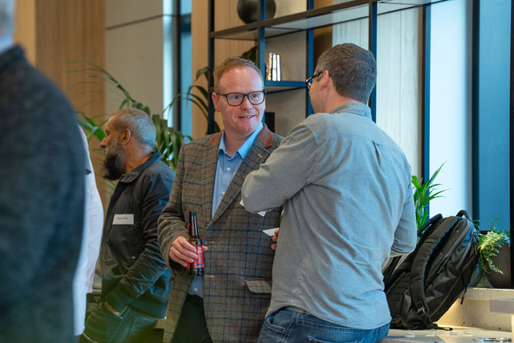 Two attendees talking beside a window at the Hub
