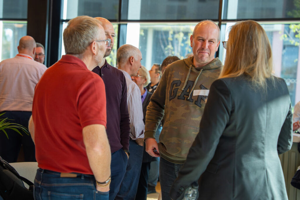 Attendees talking beside a window at the Hub