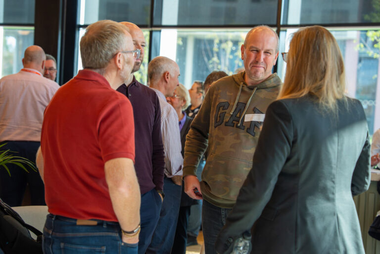Attendees talking beside a window at the Hub